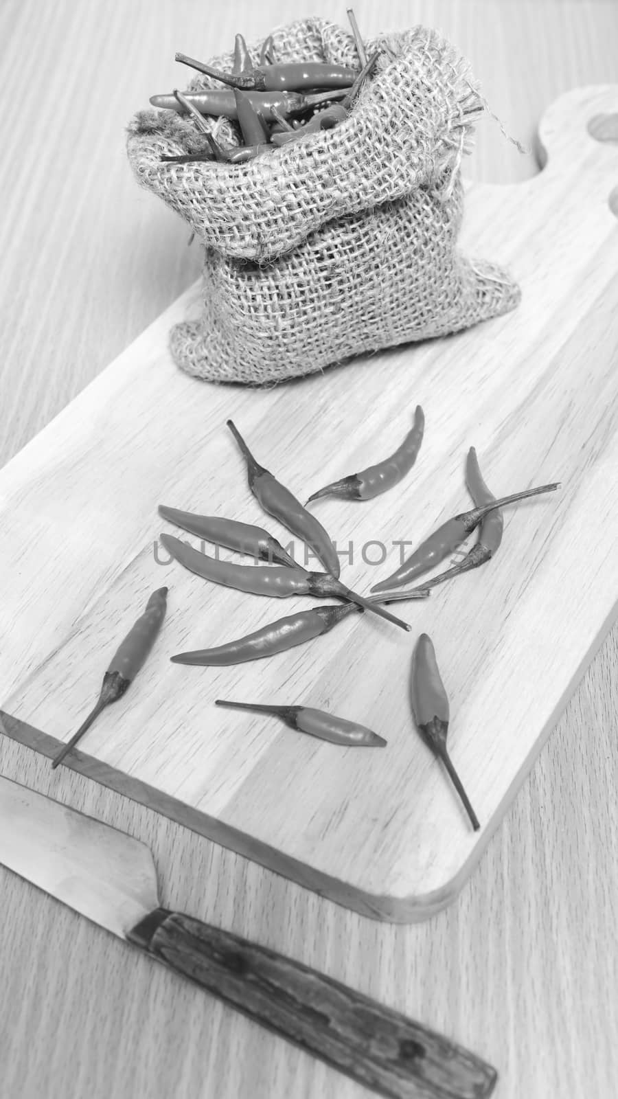 red chili peppers on cutting board over wood table background black and white tone color style