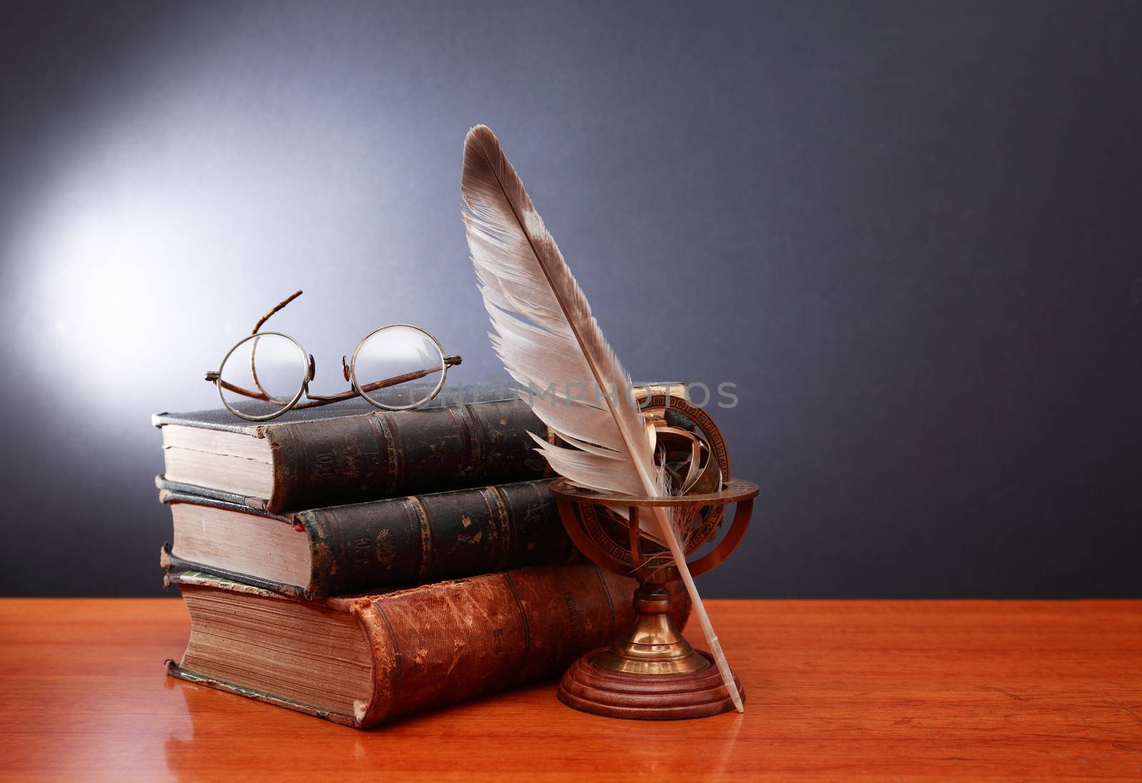 Vintage still life with quill pen near book and spectacles on dark background