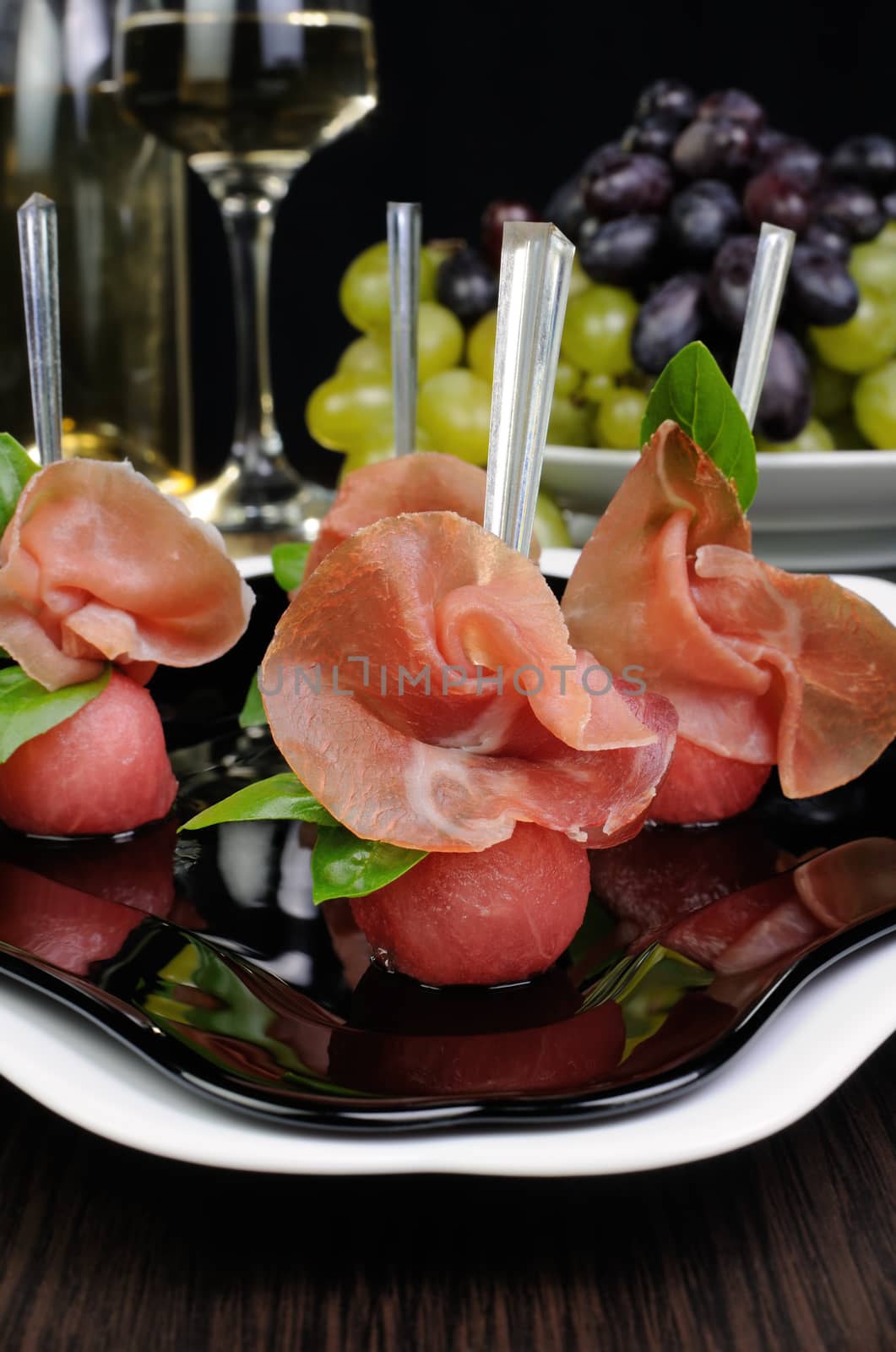 Canape of watermelon balls slice of gammon with basil