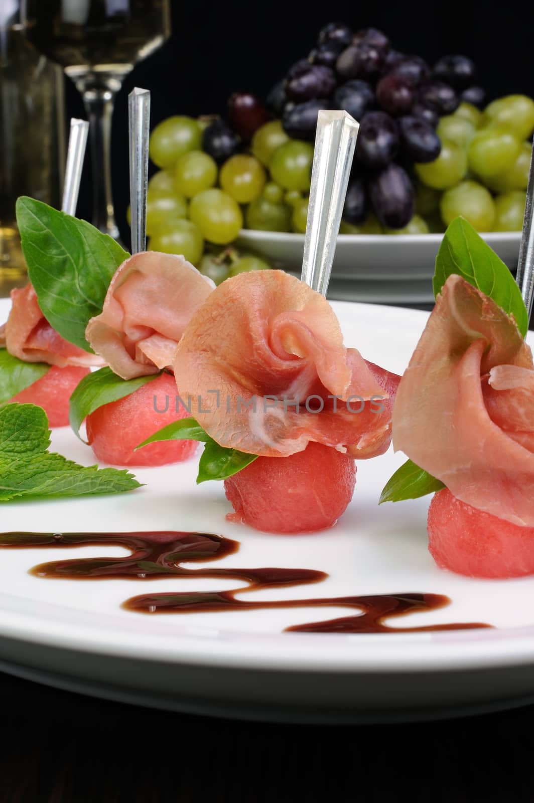 Canape of watermelon balls slice of gammon with basil