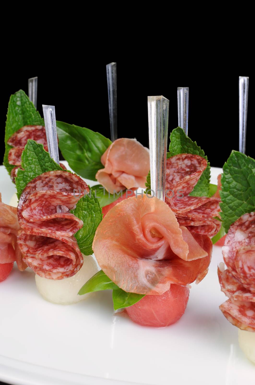 Canape of watermelon balls with a melon with gammon and salami