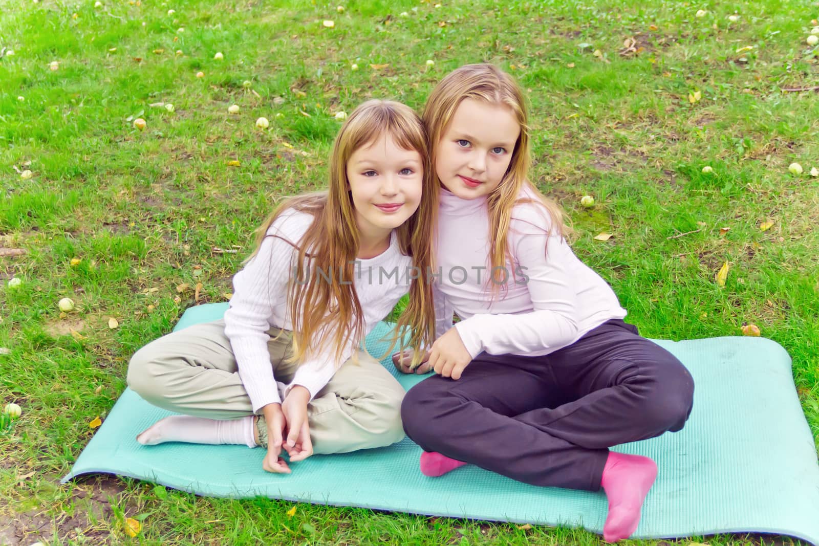 Photo of two girls sitting on grass in summer