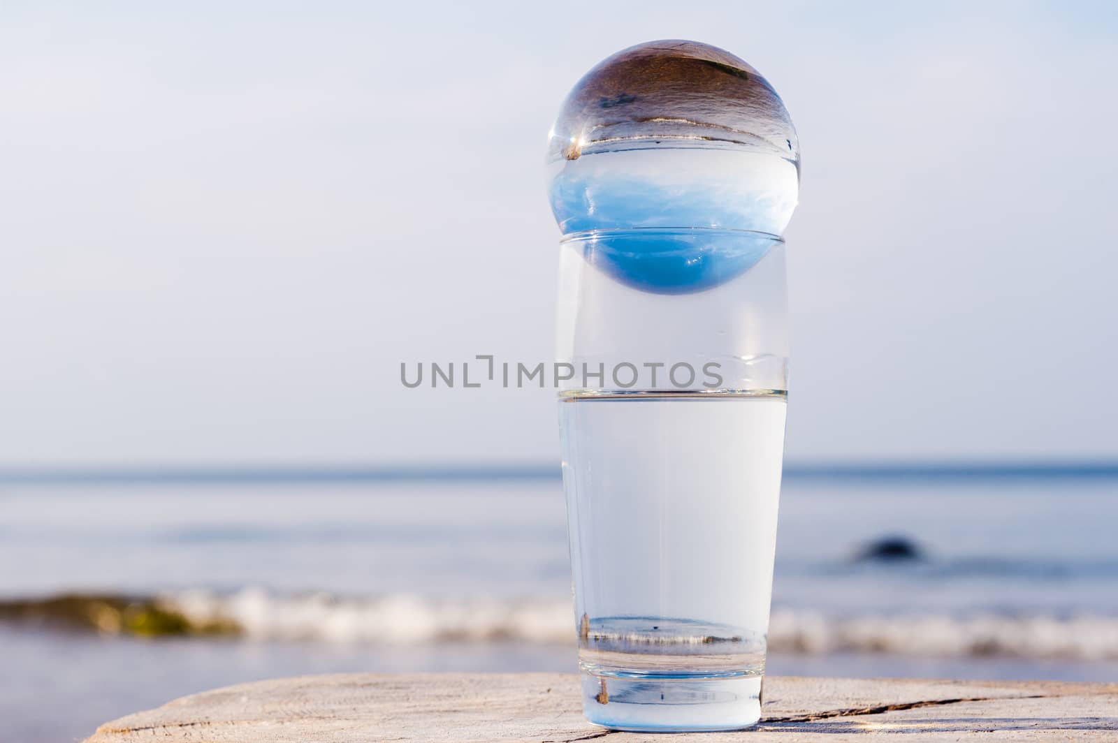 Crystal ball in a glass with water on the seacoast