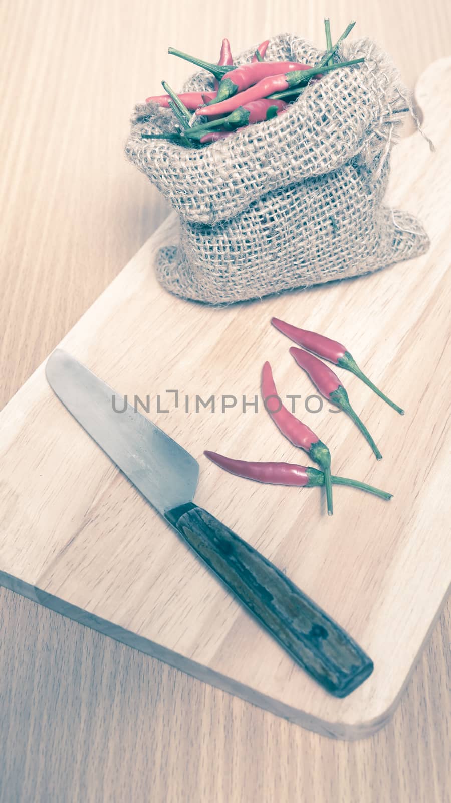 red chili peppers on cutting board over wood table background vintage style