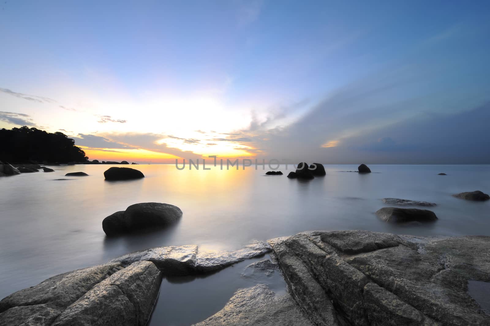 Sunrise at rocky tropical beach.