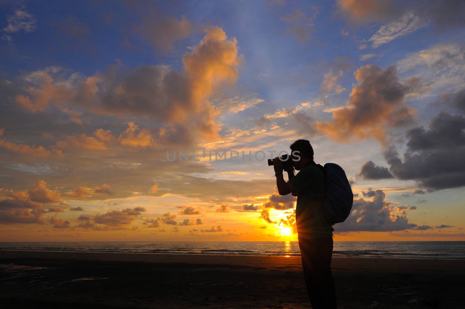 Silhouette a photographer taking pictures of sunrise on a rock,  by shahreen