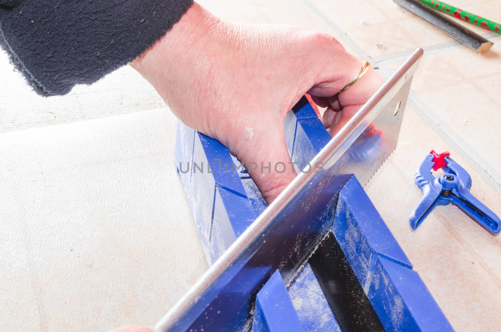 Hand of a worker with miter saw against a bright background.