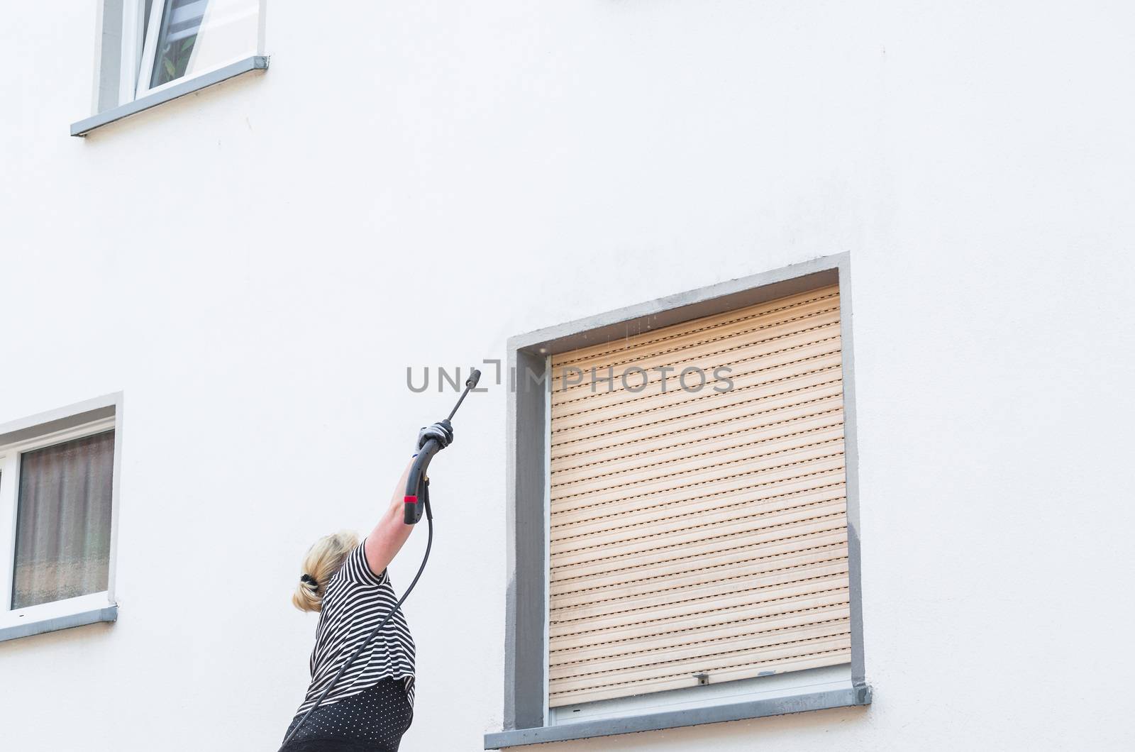 Exterior cleaning and building cleaning a gable wall with high pressure water jet.