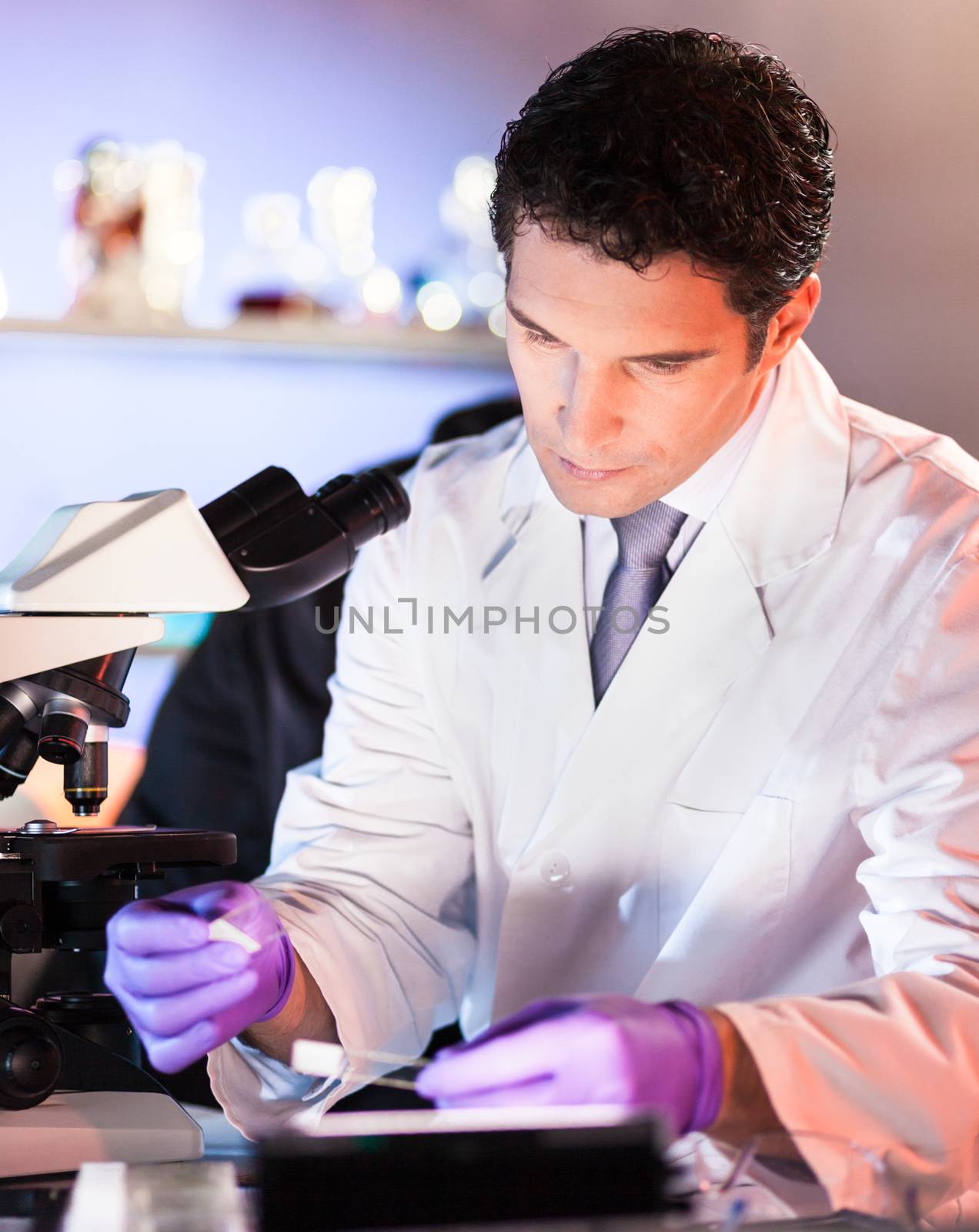 Life scientist researching in laboratory. Attractive young male scientist looking at the microscope slides in laboratory. Healthcare and biotechnology concept.