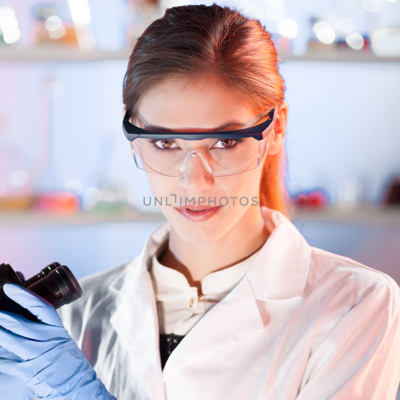 Life scientist researching in laboratory. Portrait of a attractive, young, confident female health care professional microscoping in hes working environment. Healthcare and biotechnology.