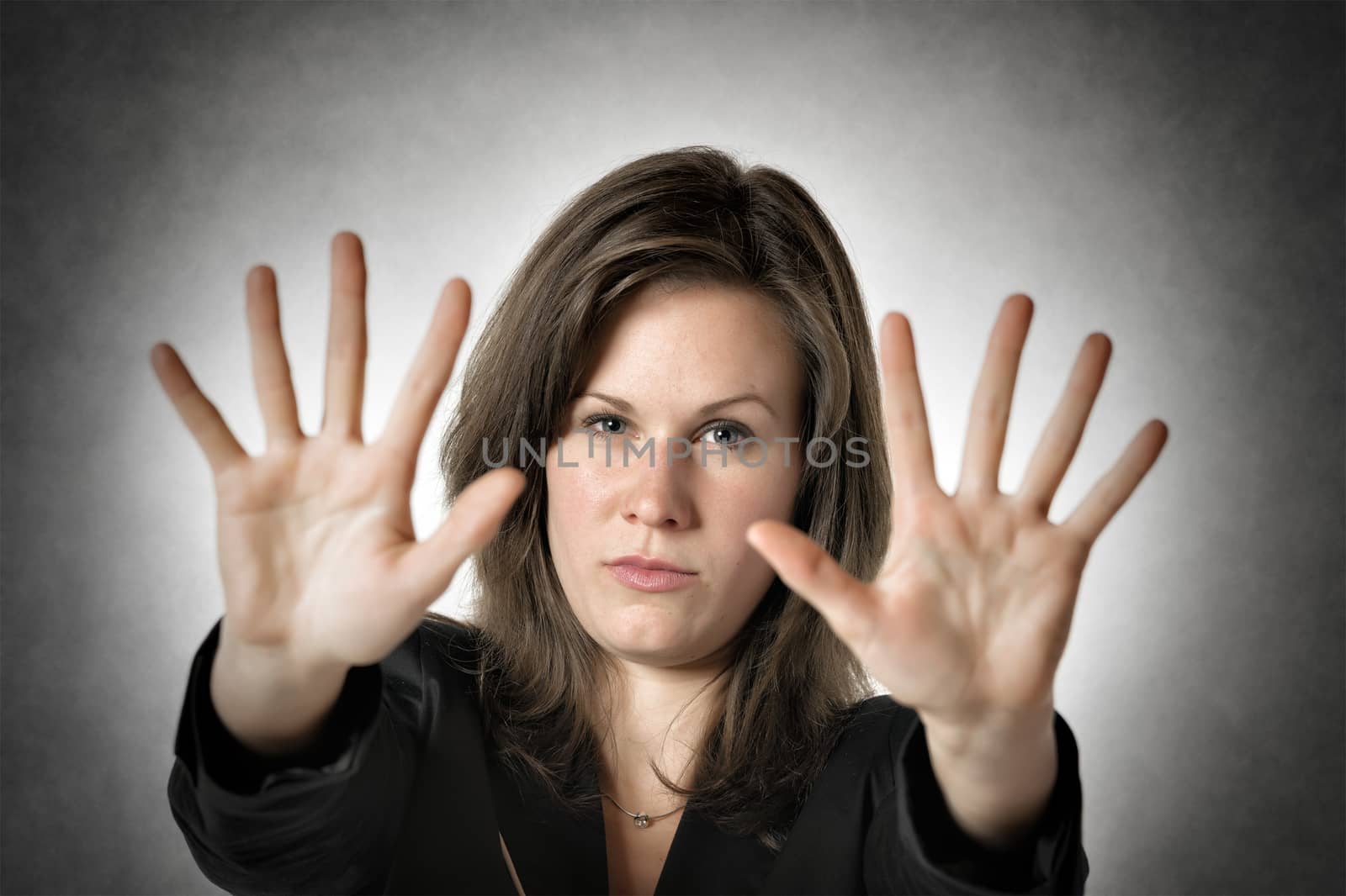 Business woman in black suit holds both hand up to stop someone or something