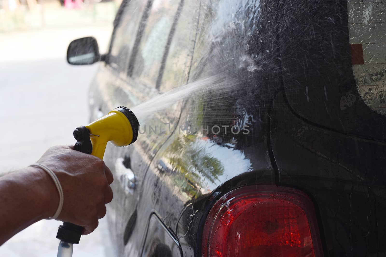 closed up the man use rubber tube to washing a car