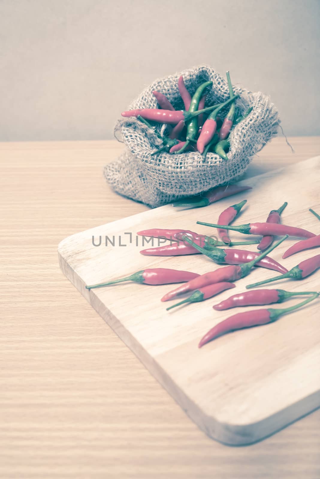 red chili peppers on cutting board over wood table background vintage style