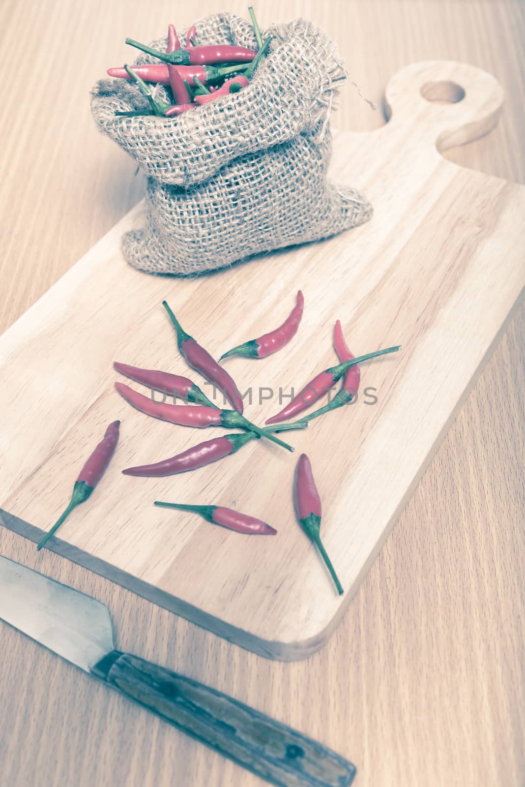 red chili peppers on cutting board over wood table background vintage style