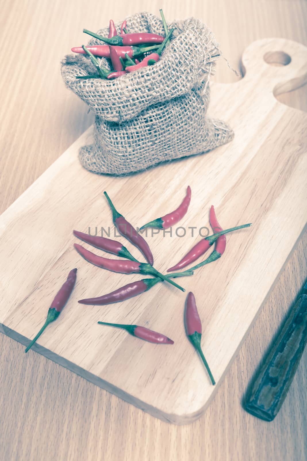 red chili peppers on cutting board over wood table background vintage style