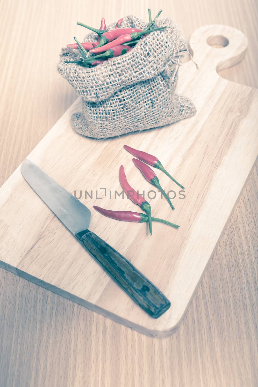 red chili peppers on cutting board over wood table background vintage style