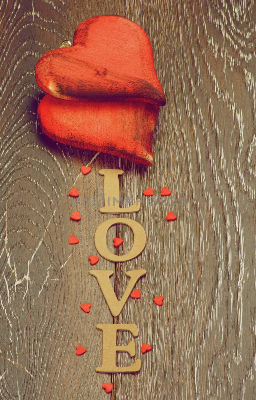 Two Wooden Red Hearts and Cardboard Word Love isolated on Dark Hardwood background. Retro Styled