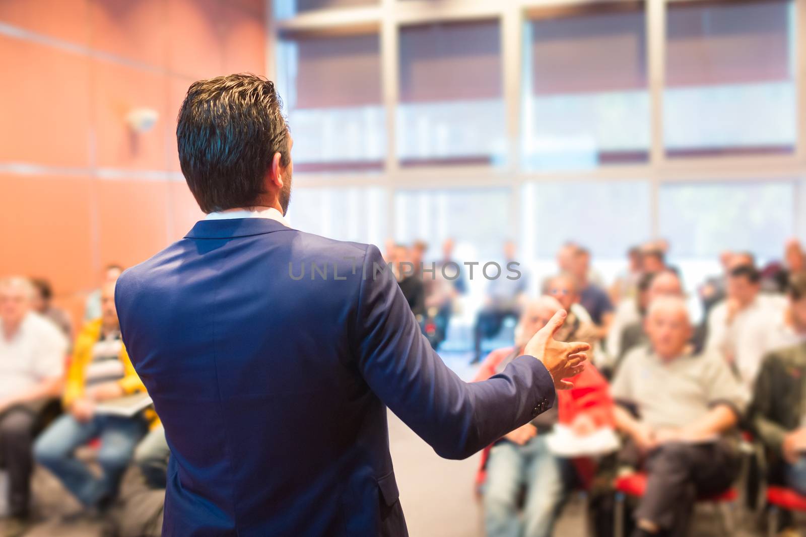 Speaker at Business Conference with Public Presentations. Audience at the conference hall. Entrepreneurship club. Rear view. Horisontal composition. Background blur.