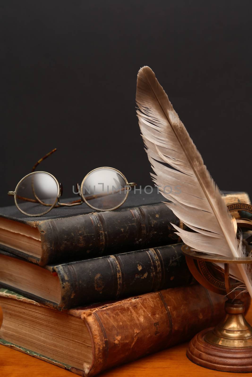 Literature concept. Vintage still life with quill pen near book and spectacles on dark background