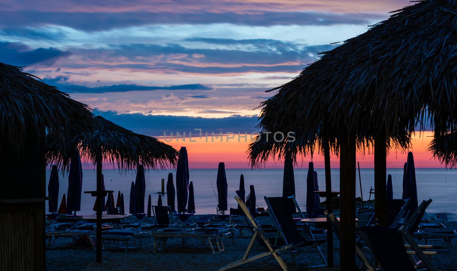 late summer dawn in a beach with chairs, and straw umbrellas