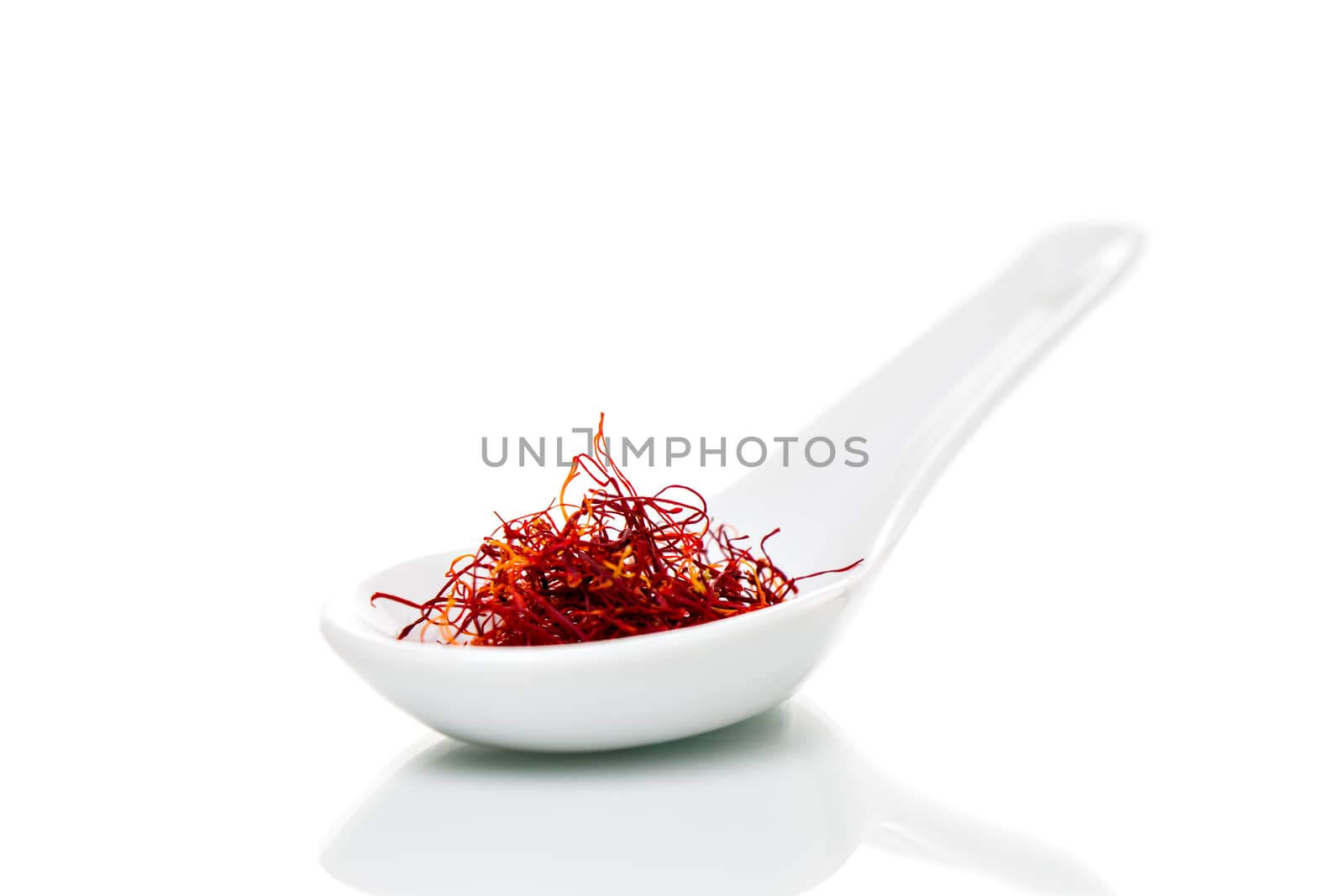 Saffron (Crocus sativus) threads on a white porcelain spoon