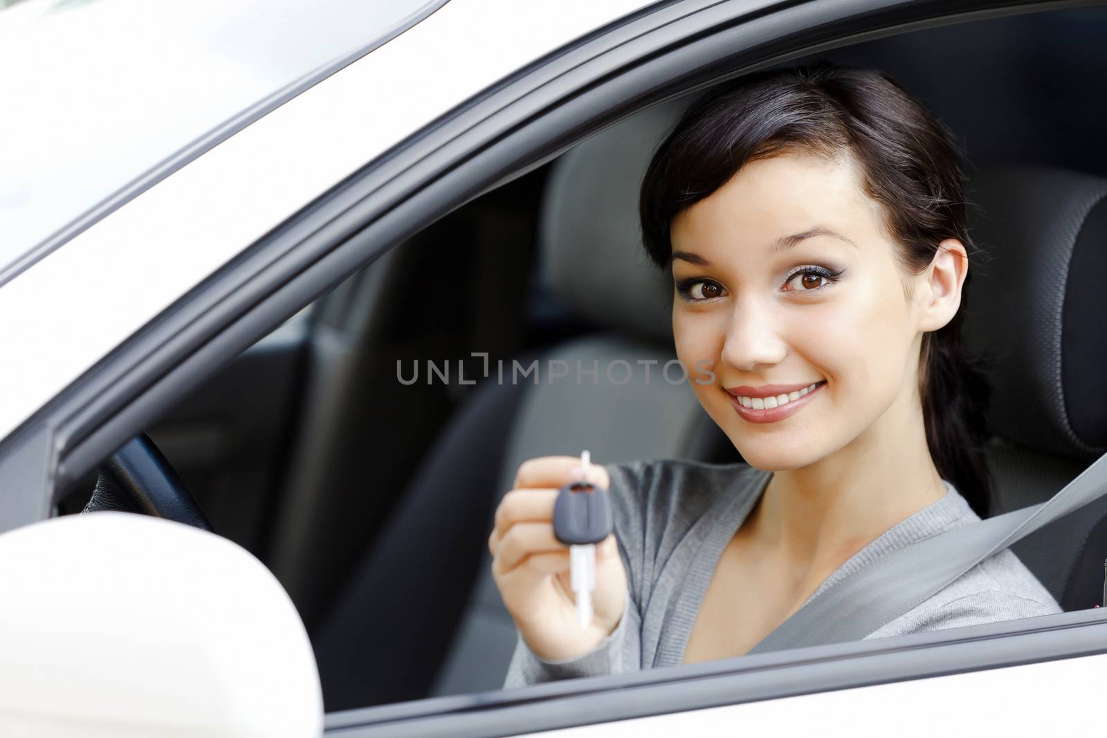 Pretty girl in a car showing the key