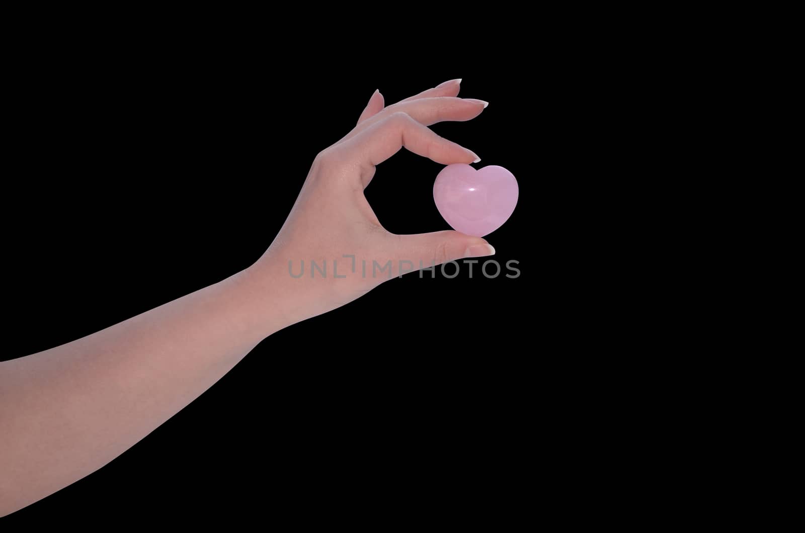 Hand holding Rose Quartz heart isolated on black background
