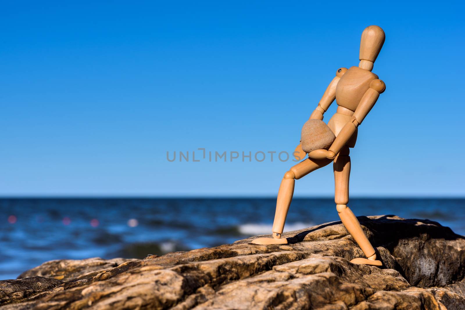 Mannequin carries a heavy stone on the coast