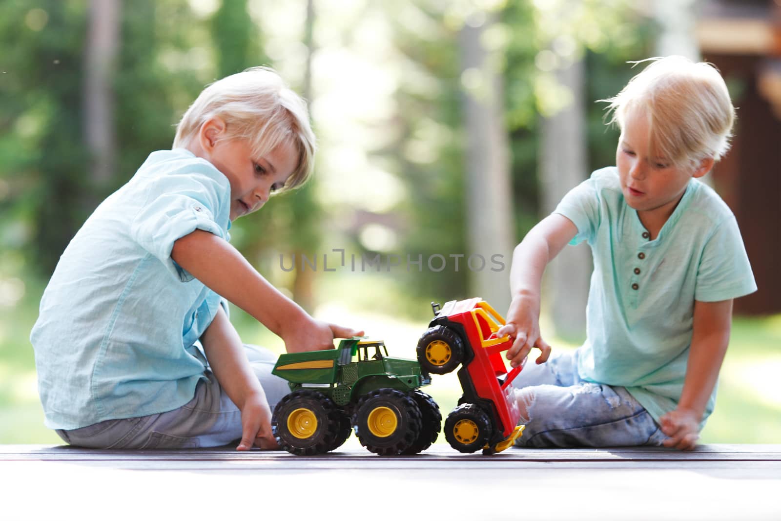 two brothers playing outdoors with toy cars