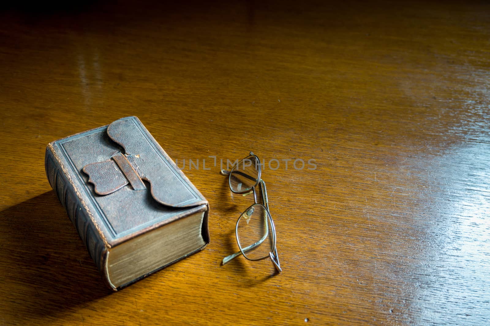 Closed antique 19th century Bible-Songbook with Glasses on a wooden table