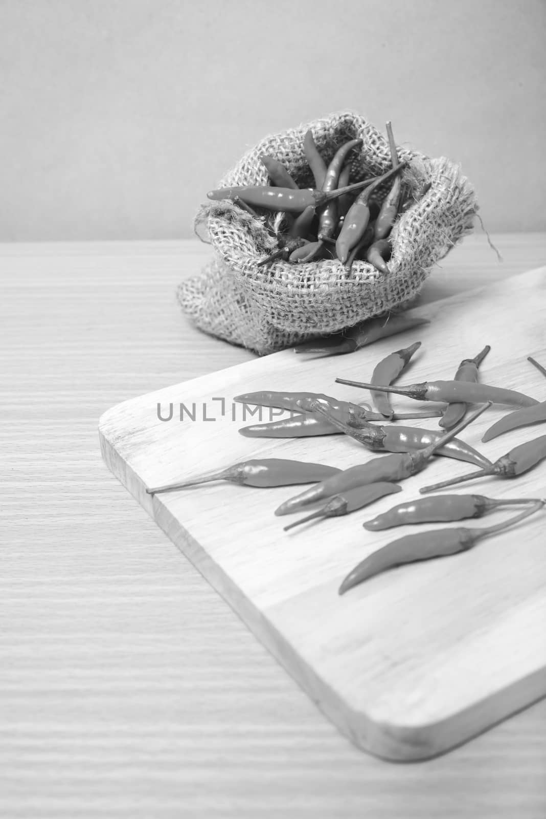 red chili peppers on cutting board over wood table background black and white tone color style