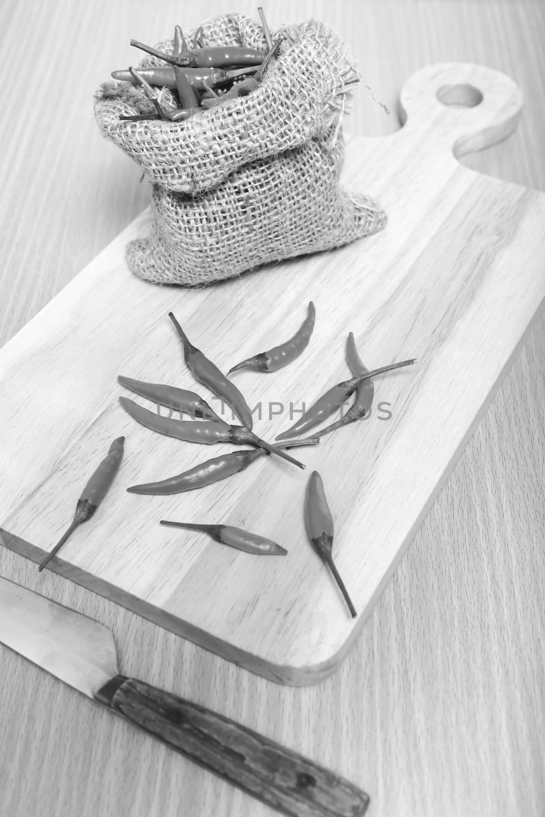 red chili peppers on cutting board over wood table background black and white tone color style