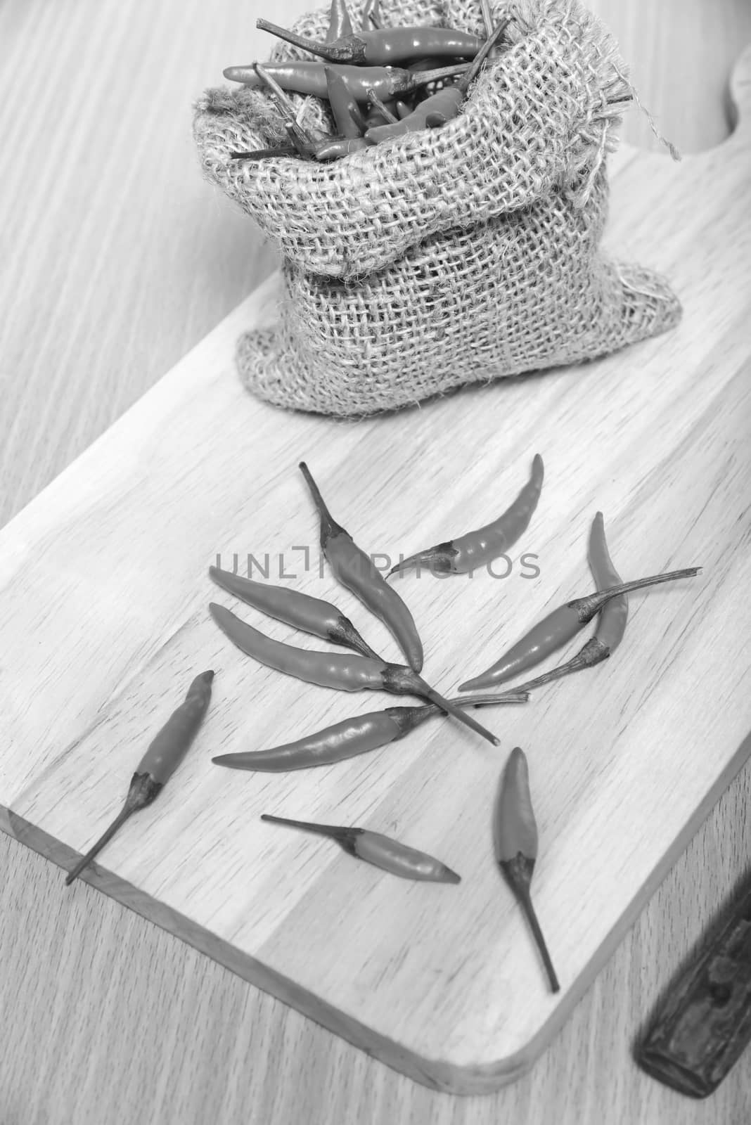 red chili peppers on cutting board over wood table background black and white tone color style