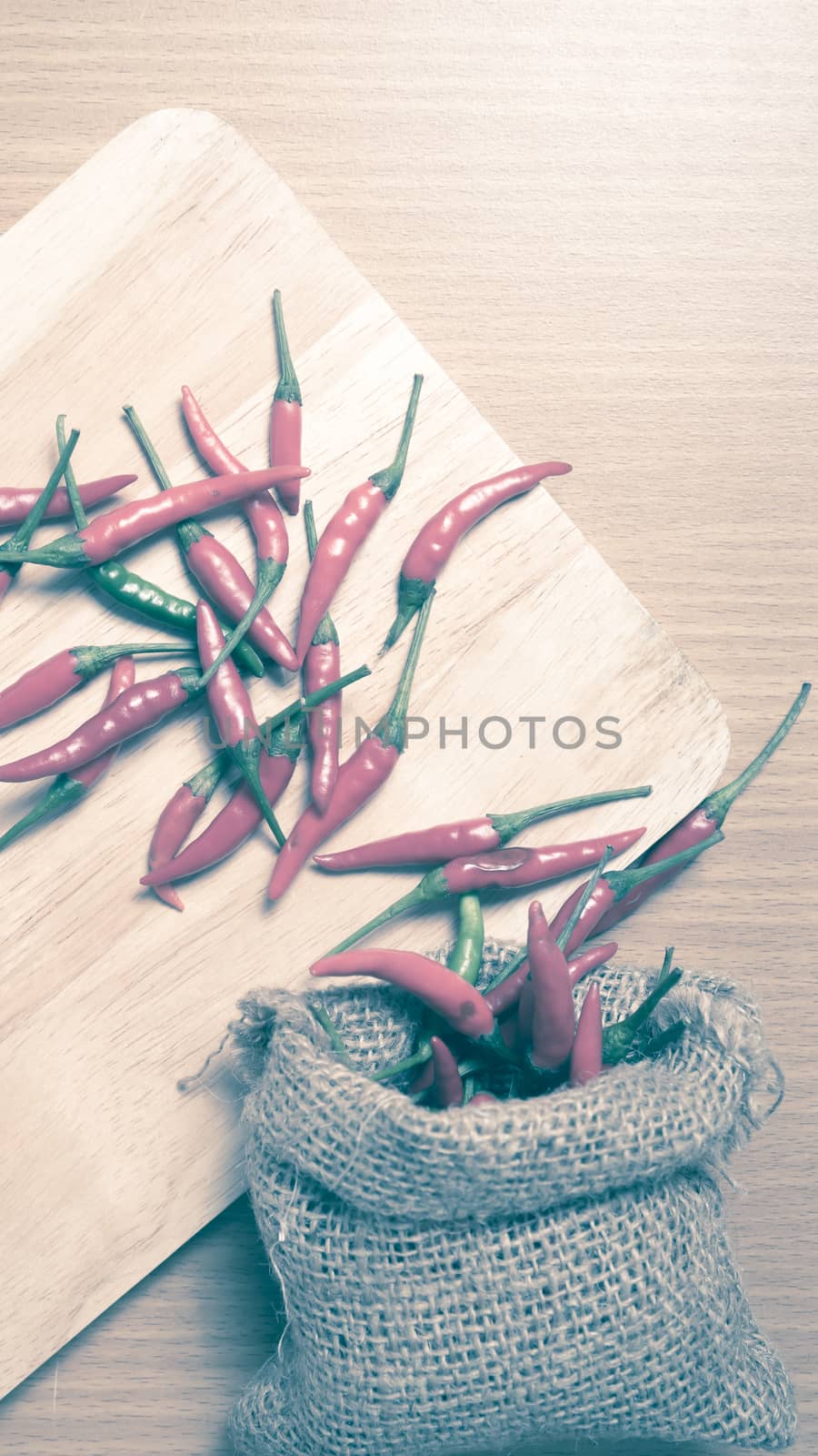 red chili peppers on cutting board over wood table background vintage style