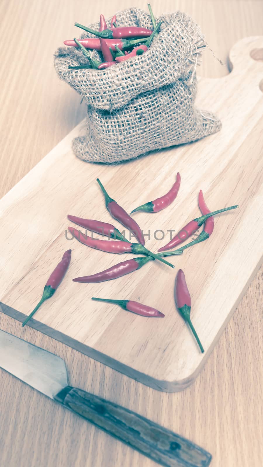 red chili peppers on cutting board over wood table background vintage style