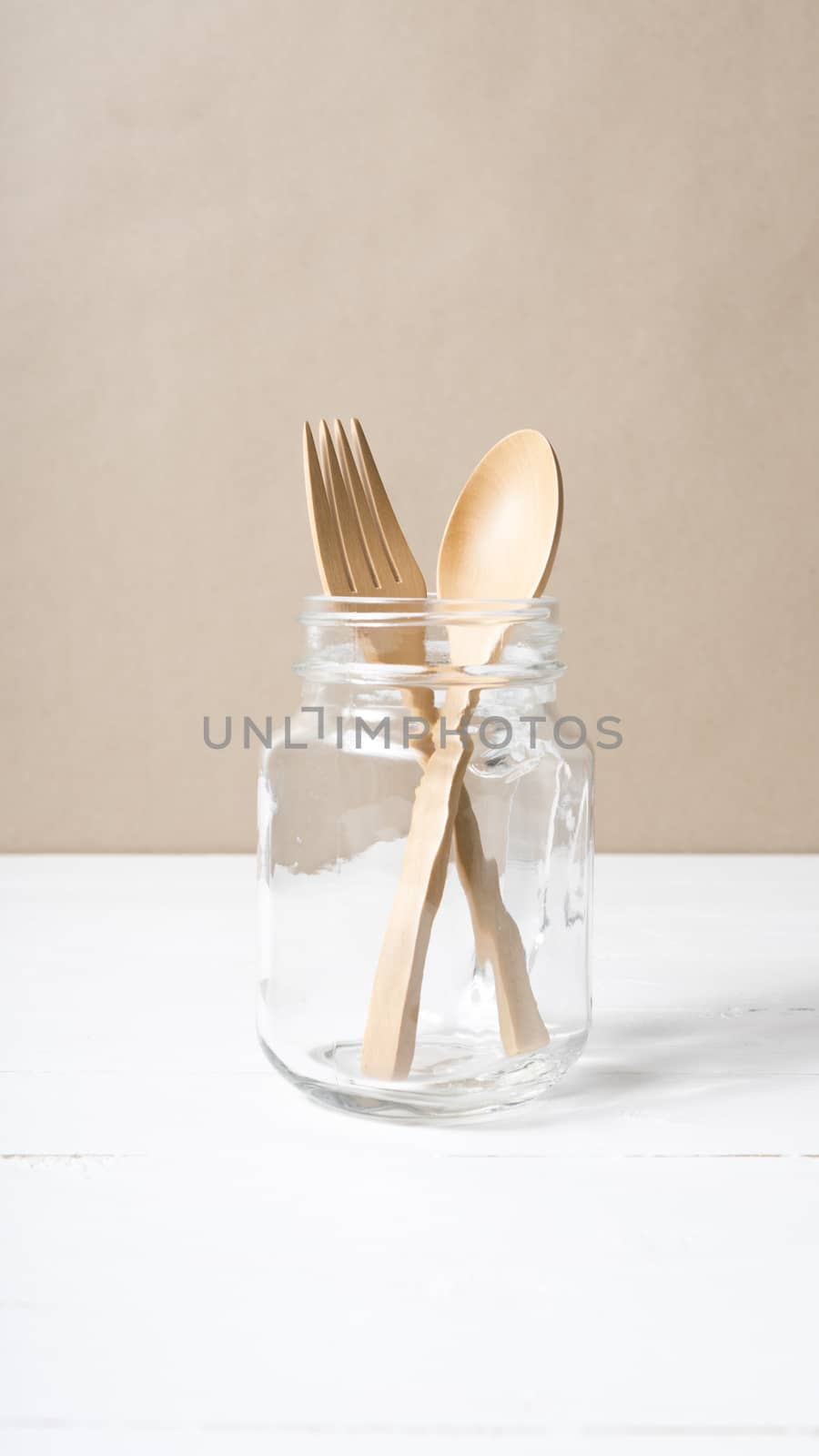 wood spoon and fork with glass over white table