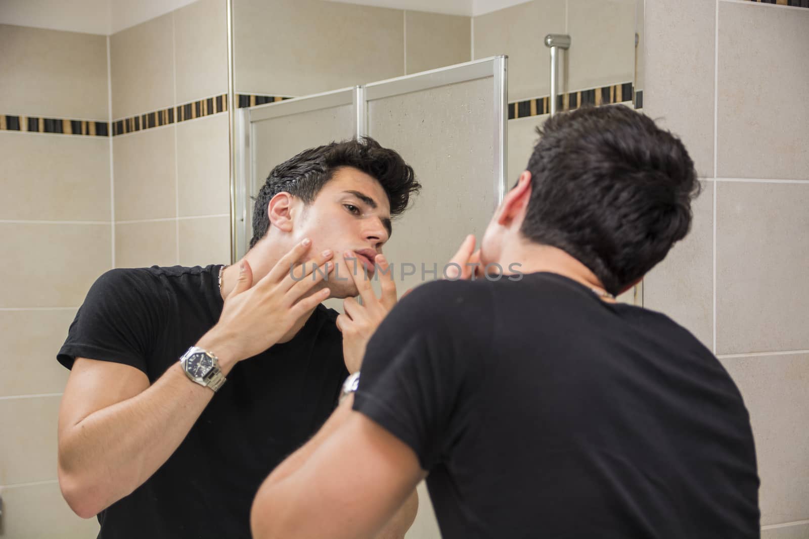 Handsome Young Man in Bathroom Touching his Face, Squeezing a Spot or Examining Blemishes