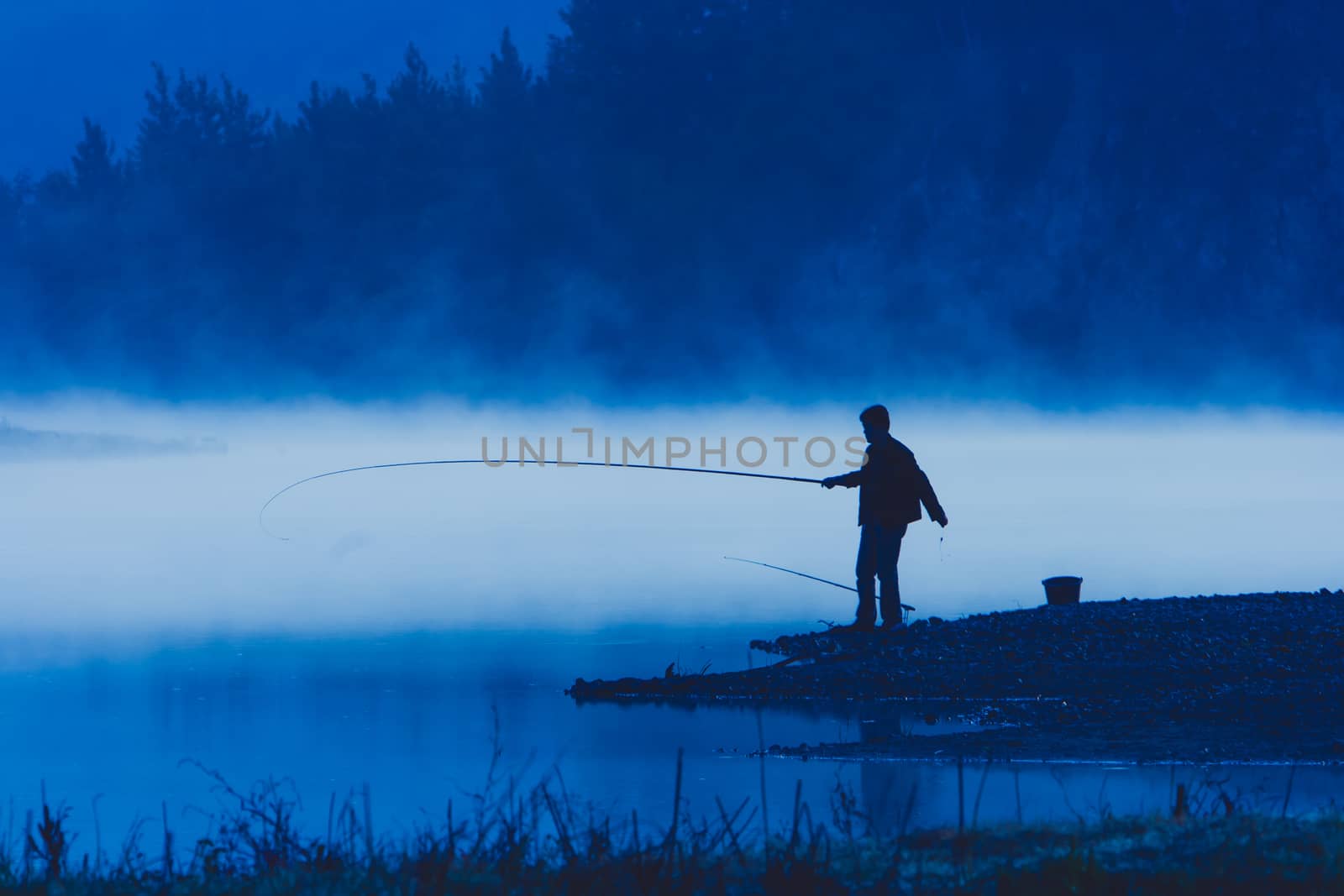 Man fishing at river shore  by kiankhoon