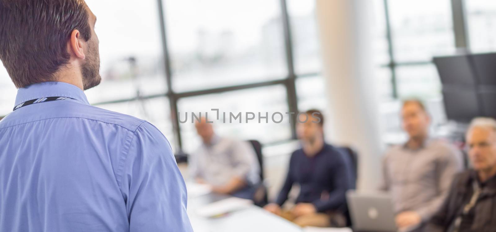 Business man making a presentation at office. Business executive delivering a presentation to his colleagues during meeting or in-house business training, explaining business plans to his employees. 