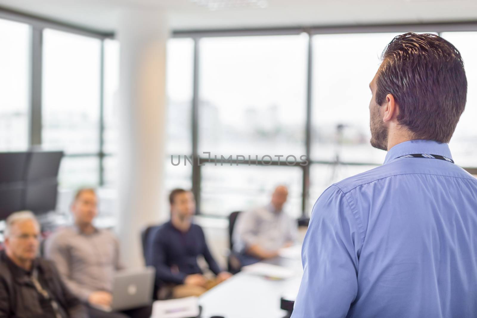 Business man making a presentation at office. Business executive delivering a presentation to his colleagues during meeting or in-house business training, explaining business plans to his employees. 