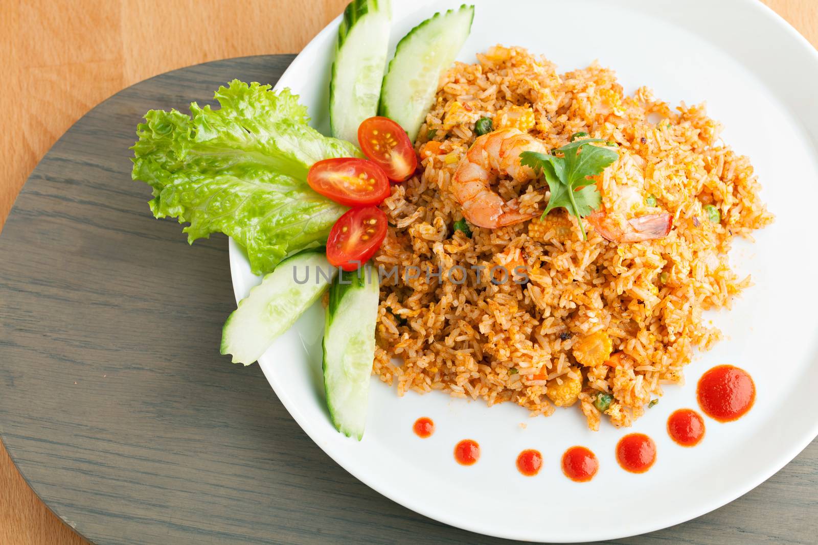 Sriracha shrimp fried rice dish with garnish dots of siracha sauce.