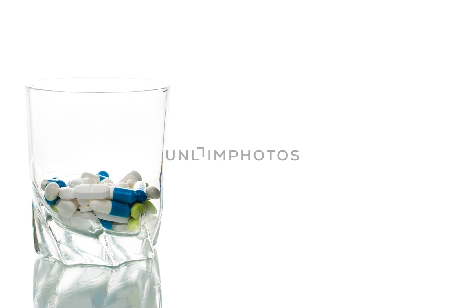 Many colorful tablets in a glass, isolated
