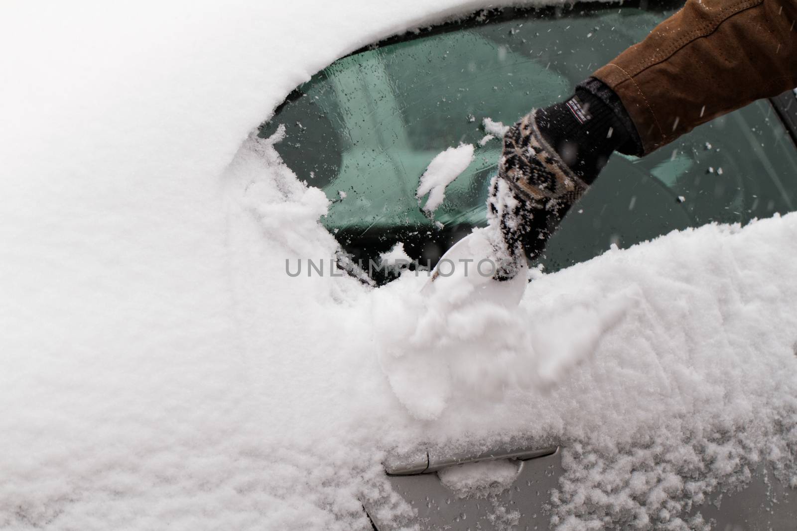 Man scraping snow and ice from car window