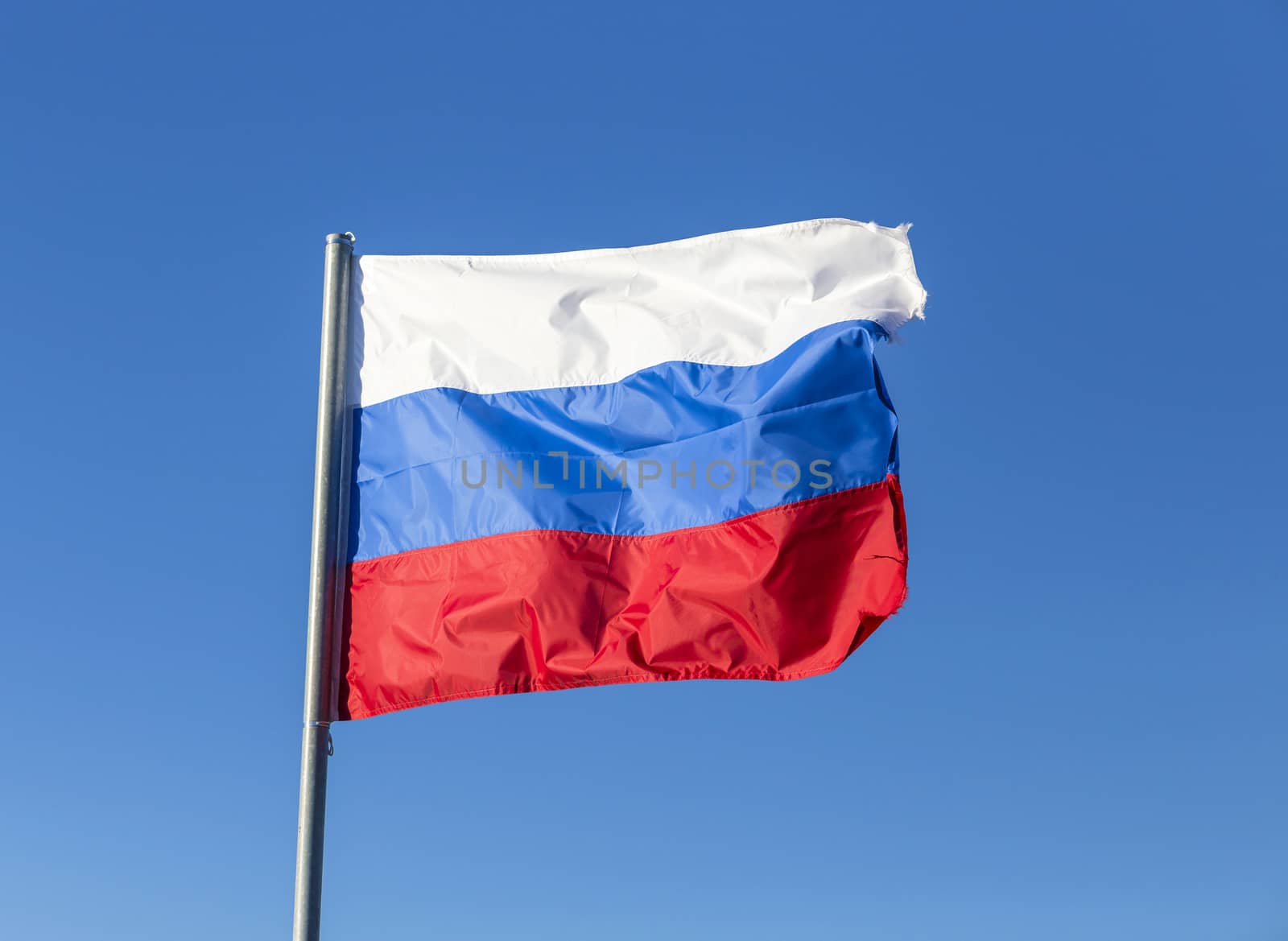 Russian flag, growing in the wind with blue sky as background