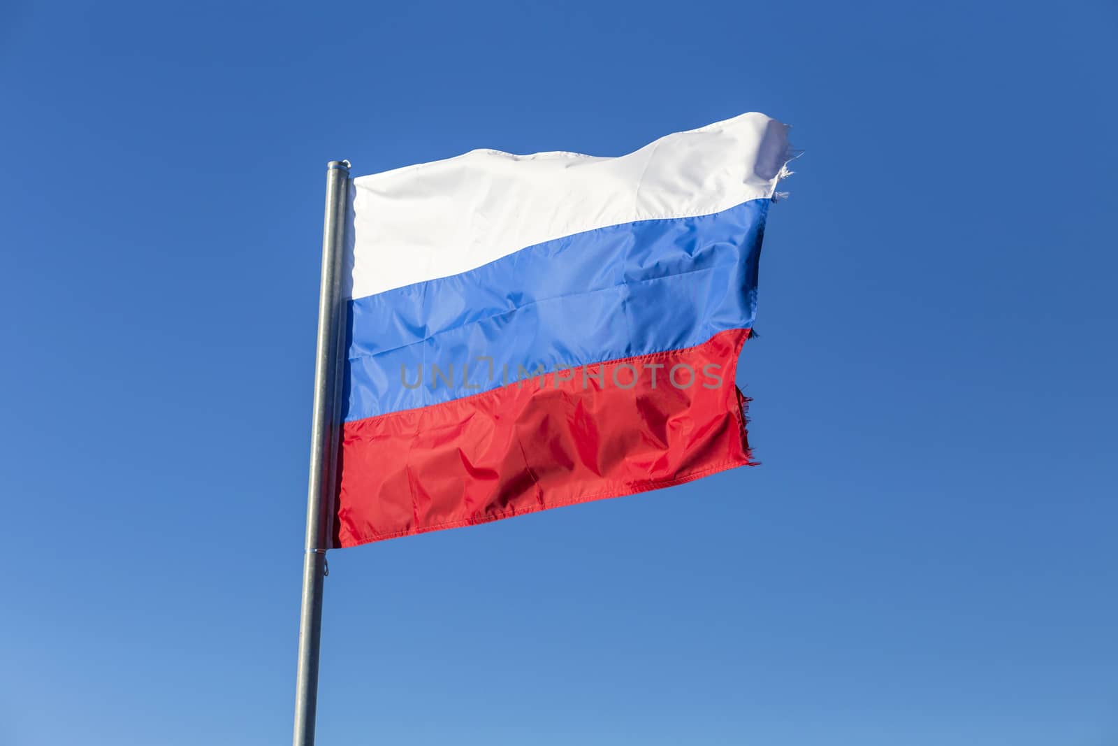 Russian flag, growing in the wind with blue sky as background