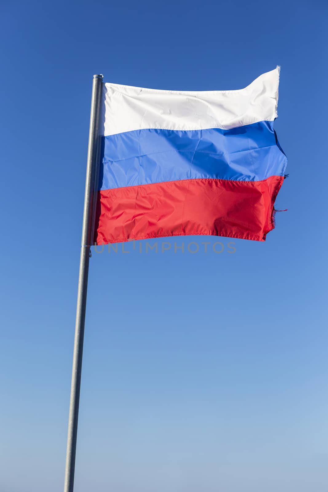 Russian flag, growing in the wind with blue sky as background