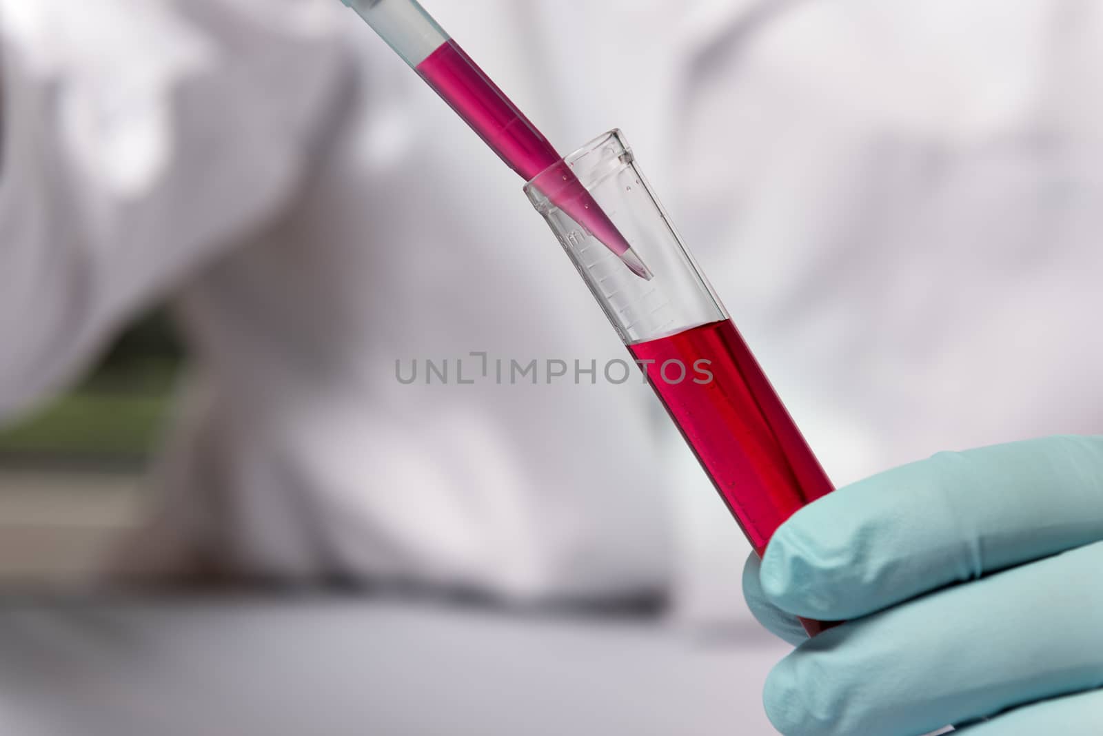 Closeup hand of chemist with a red liquid