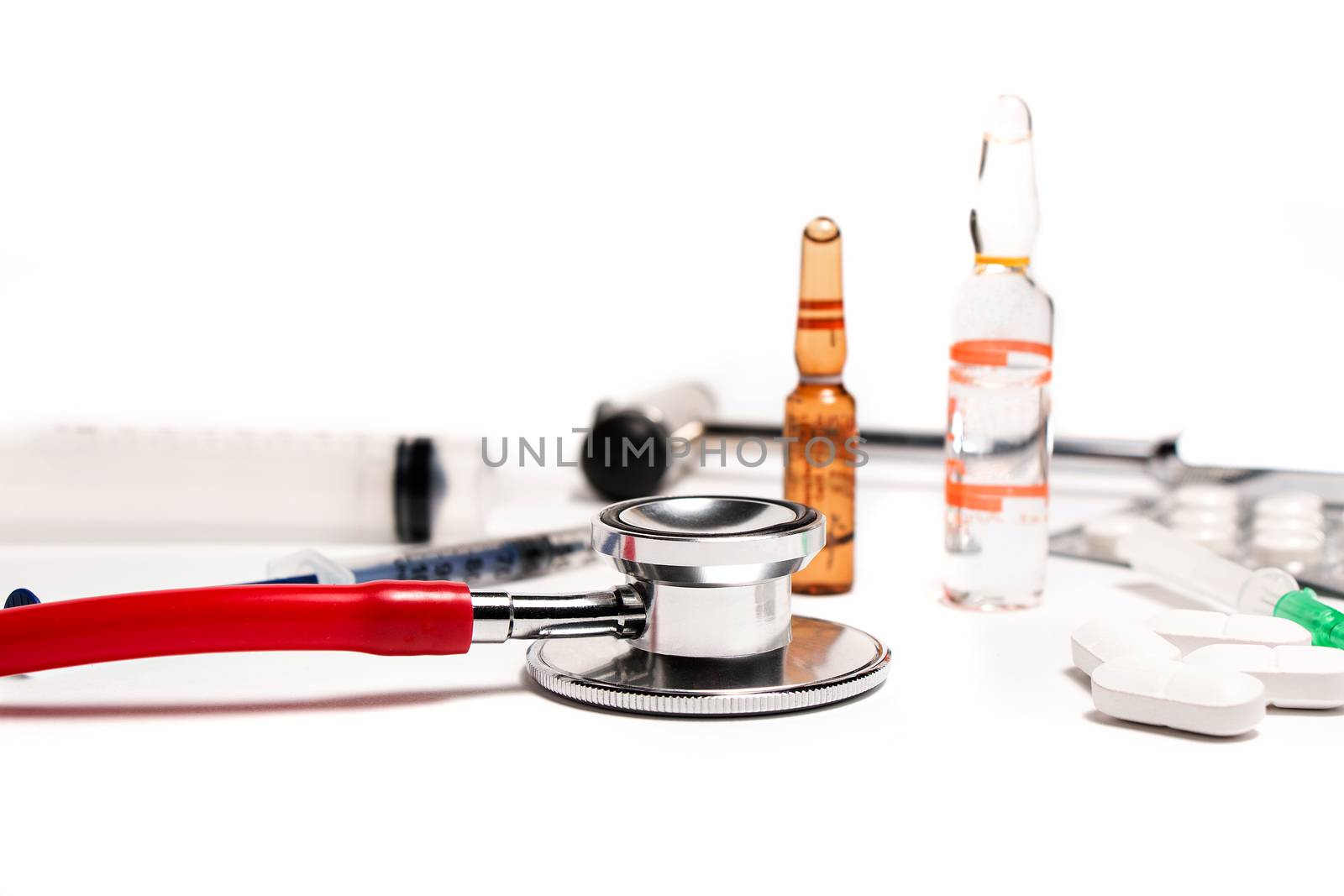 Tablets and a syringe lying on a white table