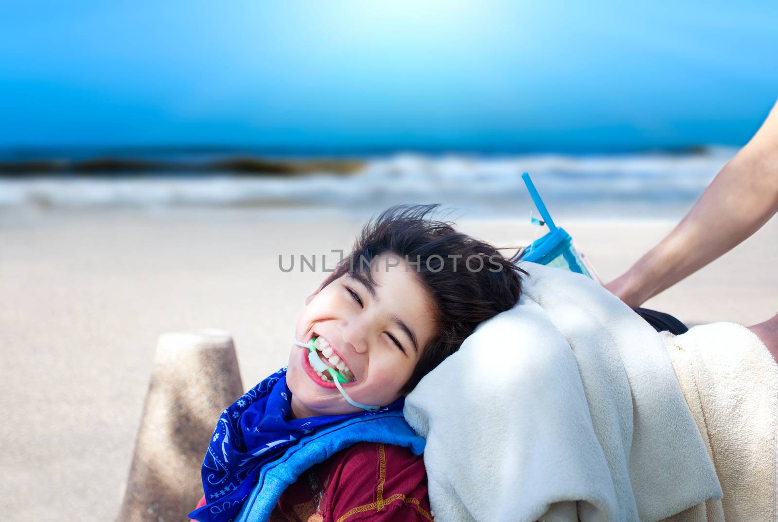 Happy disabled boy being pushed in wheelchair with ocean beach i by jarenwicklund
