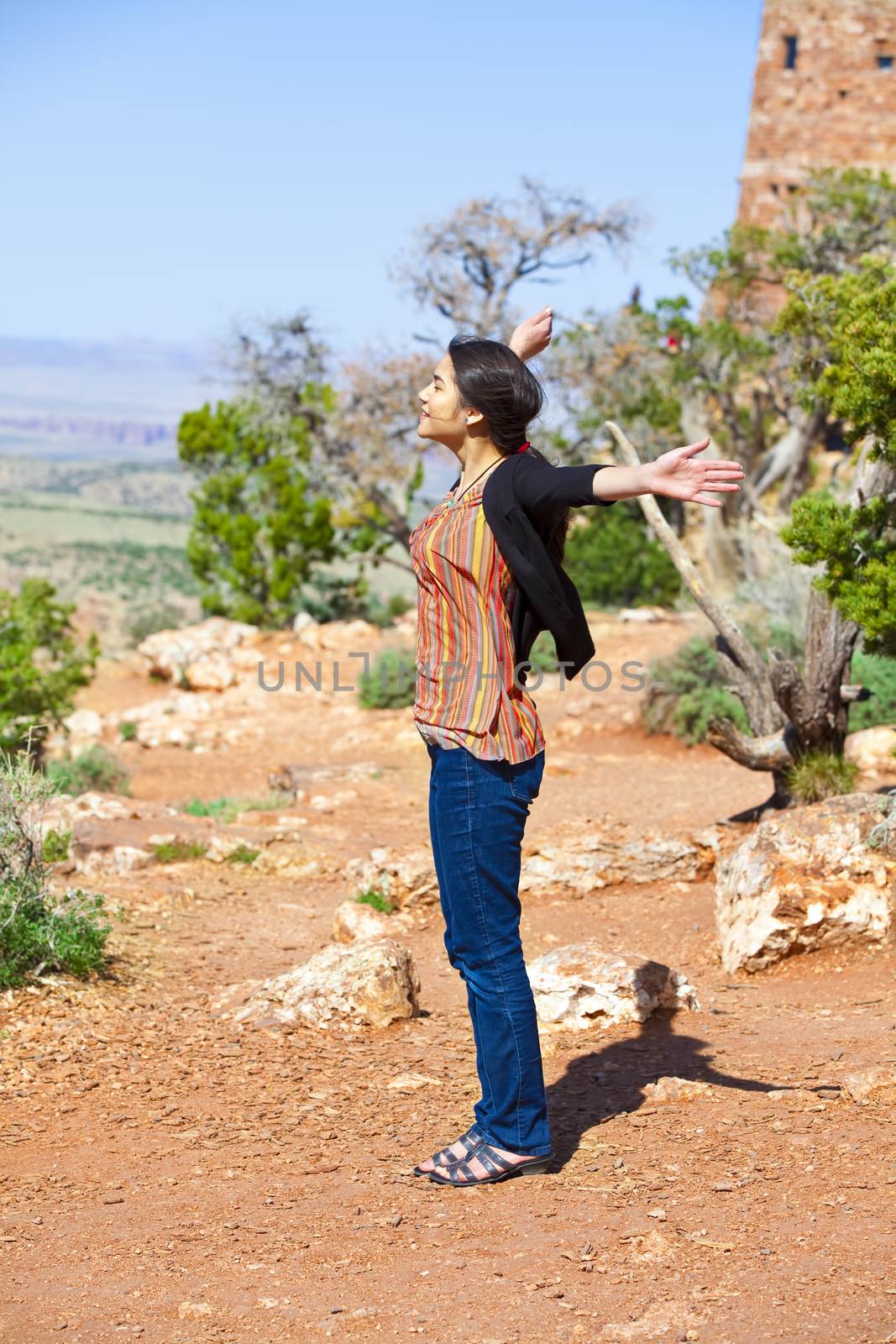 Biracial teen girl raising arms in praise at the Grand Canyon, happy expression